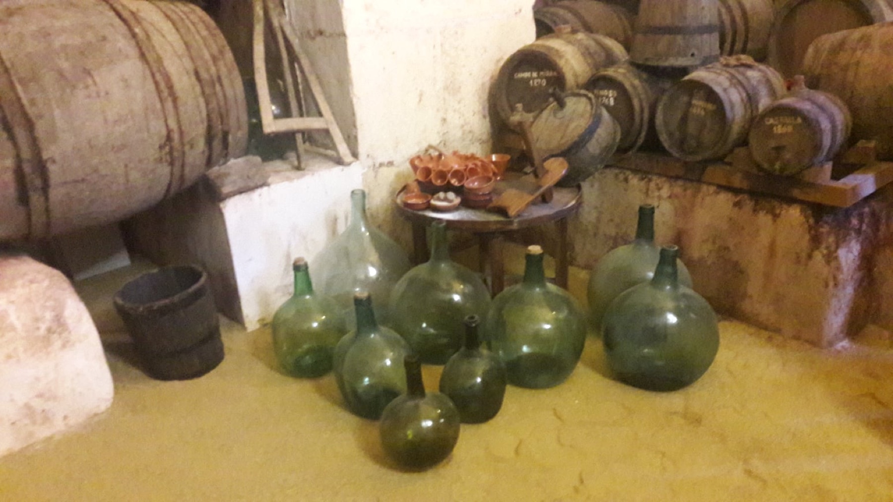 Damajuanas de vidrio junto a los toneles