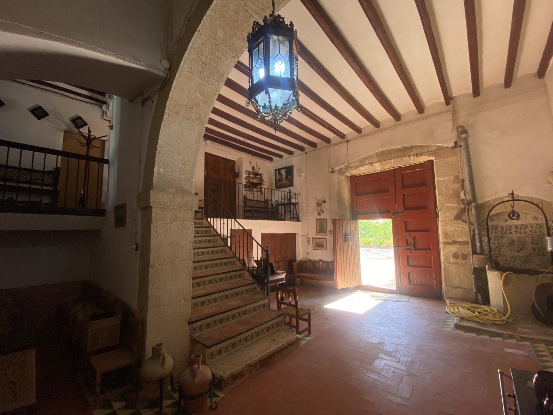 El vestíbulo de entrada, con su arco de piedra, la escalera y la puerta abierta al jardín